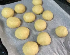 Step <p><br></p><p>Forre una bandeja de horno con papel de hornear.</p><p>Ponga en el vaso el azúcar, la piel de limón y la de naranja y triture 20 seg/vel 10.</p><p>Con la espátula, baje el azúcar aromatizada hacia el fondo del vaso. Añada la leche, la mantequilla, los huevos, la levadura prensada, el agua de azahar, la harina de fuerza, la sal y la bola de masa. Mezcle 30 seg/vel 6 y a continuación, amase Amasar /3 min (la masa se moverá formando una bola). Sin desmontar el vaso de la máquina y sin quitar el cubilete, cubra el vaso y la máquina con dos paños o una bolsa isotérmica para congelados. Déjelreposar hasta que la masa salga por la abertura (aprox. 1 hora, en función de la temperatura ambiente).</p><p>Con la espátula, baje la masa hacia el fondo del vaso y vuelva a amasar Amasar /1 min. Retire la masa del vaso (estará blanda) y póngala sobre una superficie enharinada. </p><p>Pese la masa y divida el peso entre 13, hacemos 13 bolitas y las vamos redondeando y disponiendo encima de la bandeja de horno con el papel vegetal</p><p><br></p> illustration